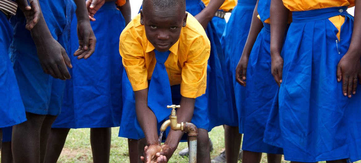 युगांडा में एक प्राइमरी स्कूल में, बच्चे नल के पानी से हाथ धोते हुए.