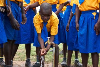 युगांडा में एक प्राइमरी स्कूल में, बच्चे नल के पानी से हाथ धोते हुए.