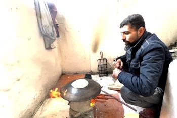अब्दुल मजीद, पशुओं के चारे से, अपने परिवार के लिए रोटी बनाते हुए. आग चलाने के लिए लकड़ियाँ भी युद्ध में ध्वस्त हुईं इमारतों में से एकत्र की गई हैं.