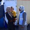 منى الزريعي، الأخصائية الاجتماعية والمرشدة النفسية لدى وكالة الأونروا في مركز للإيواء في دير البلح في غزة، (إلى اليمين) تتحدث مع إحدى الأمهات.