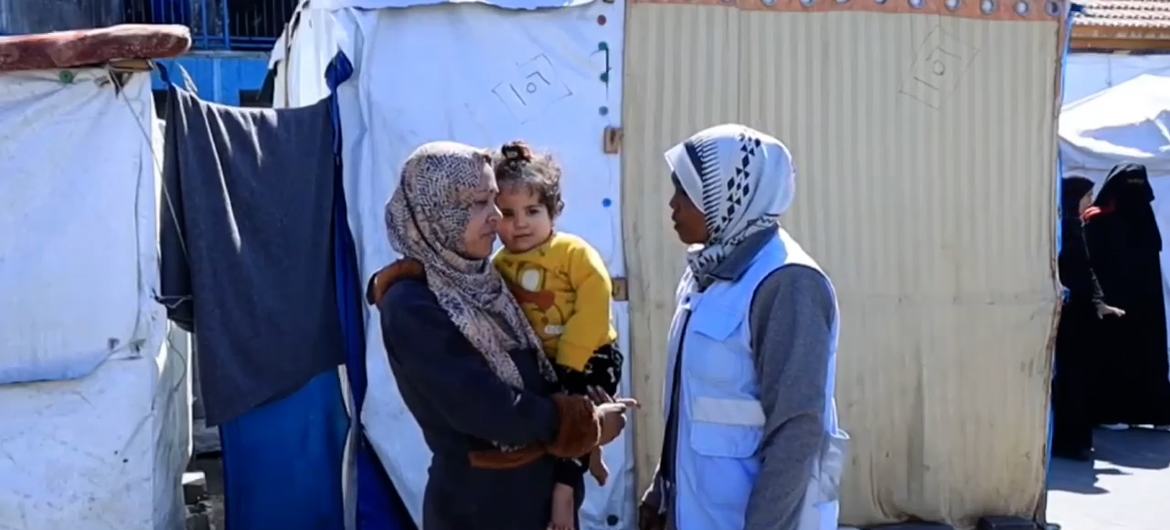 منى الزريعي، الأخصائية الاجتماعية والمرشدة النفسية لدى وكالة الأونروا في مركز للإيواء في دير البلح في غزة، (إلى اليمين) تتحدث مع إحدى الأمهات.