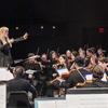 Una directora de orquesta lidera una orquesta sinfónica en un escenario.