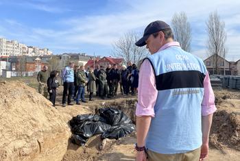 A UN staffer stands in front of a mass grave site in Bucha, Ukraine. In the background the United Nations Emergency Relief Coordinator Martin Griffiths.