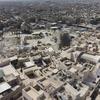 صورة جوية لمدينة الموصل في العراق، تُظهر جهود إعادة الإعمار والترميم الحضري، مع مبنى يتميز بقبة خضراء ومواقع بناء وسط أسطح منازل المدينة.