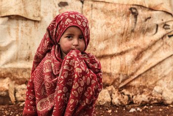 A young girl in a red patterned headscarf looks to the camera at the Khair Al-Sham IDP camp in Idleb Governorate, west of the town of Sarmada.