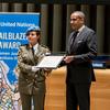 La Major Ahlem Douzi reçoit le Prix 2024 de la pionnière des Nations Unies pour les femmes spécialistes des questions judiciaires et pénitentiaires, des mains du chef de cabinet Courtenay Rattray lors d'une cérémonie.
