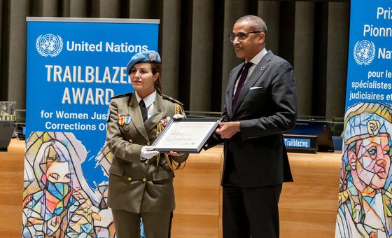 La Major Ahlem Douzi reçoit le Prix 2024 de la pionnière des Nations Unies pour les femmes spécialistes des questions judiciaires et pénitentiaires, des mains du chef de cabinet Courtenay Rattray lors d'une cérémonie.