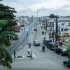 Vue aérienne d'Ogunlana Drive à Lagos, au Nigéria, montrant une large route avec des véhicules, des piétons et des bâtiments sous un ciel couvert.