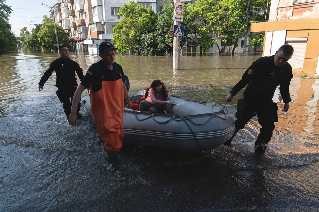 在乌克兰南部的卡霍夫卡大坝遭到破坏后，一名妇女被从洪水淹没的赫尔松街区营救出来。