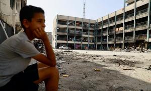 Un niño gazatí observa la destrucción de una escuela convertida en refugio y bombardeada por Israel en Gaza.