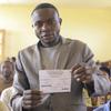 Mwanaume anashikilia karatasi yenye maandishi wakati wa mkutano huko Beni, DRC.
