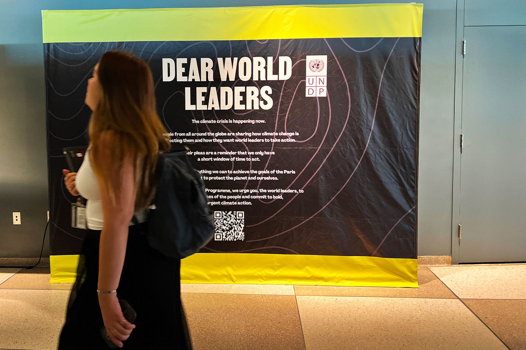 Un membre du personnel de l'ONU passe devant un panneau appelant les dirigeants mondiaux à s'engager dans une "action climatique audacieuse et urgente".
