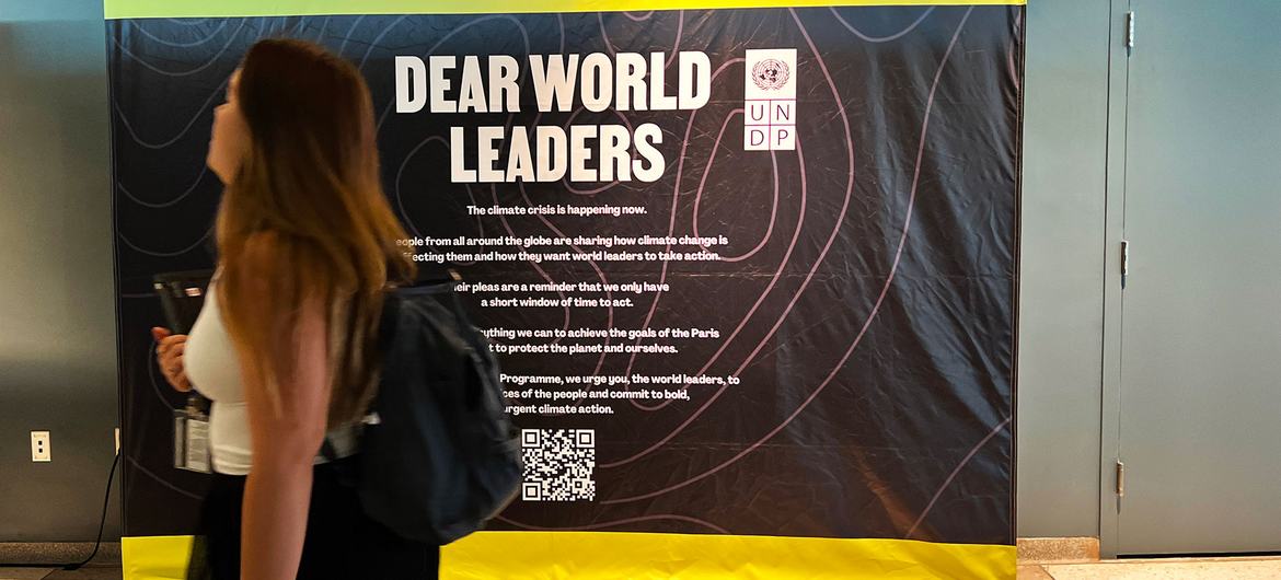 一名联合国工作人员经过一块牌子，呼吁世界各国领导人承诺采取“大胆、紧急的气候行动”。
