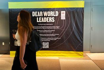 Un miembro del personal de la ONU pasa por delante de un cartel en el que se pide a los líderes mundiales que se comprometan a "una acción climática audaz y urgente".