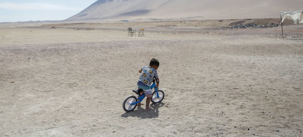 A child rides his bicycle outside a UNICEF-supported humanitarian camp for migrant families in Chile.