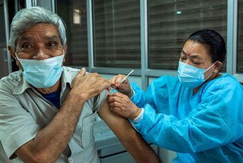 Une personne âgée reçoit un vaccin contre la COVID-19 administré par une infirmière dans un centre de vaccination à Katmandou, au Népal.