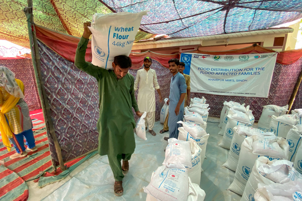 Personas afectadas por las recientes inundaciones en Pakistán recogen harina en un lugar de distribución de alimentos del PMA.