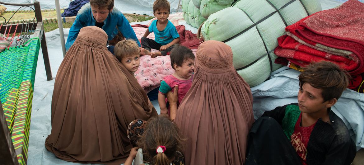 Refugiados afegãos abrigam-se numa tenda depois de serem deslocados pelas inundações de monções no distrito de Nowshera, no Paquistão.