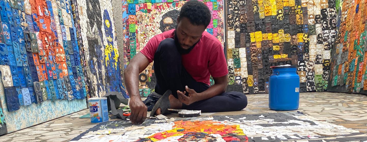 L'artiste Aristide Kouamé colle sur la toile les lettres découpées dans des tongs usagées.