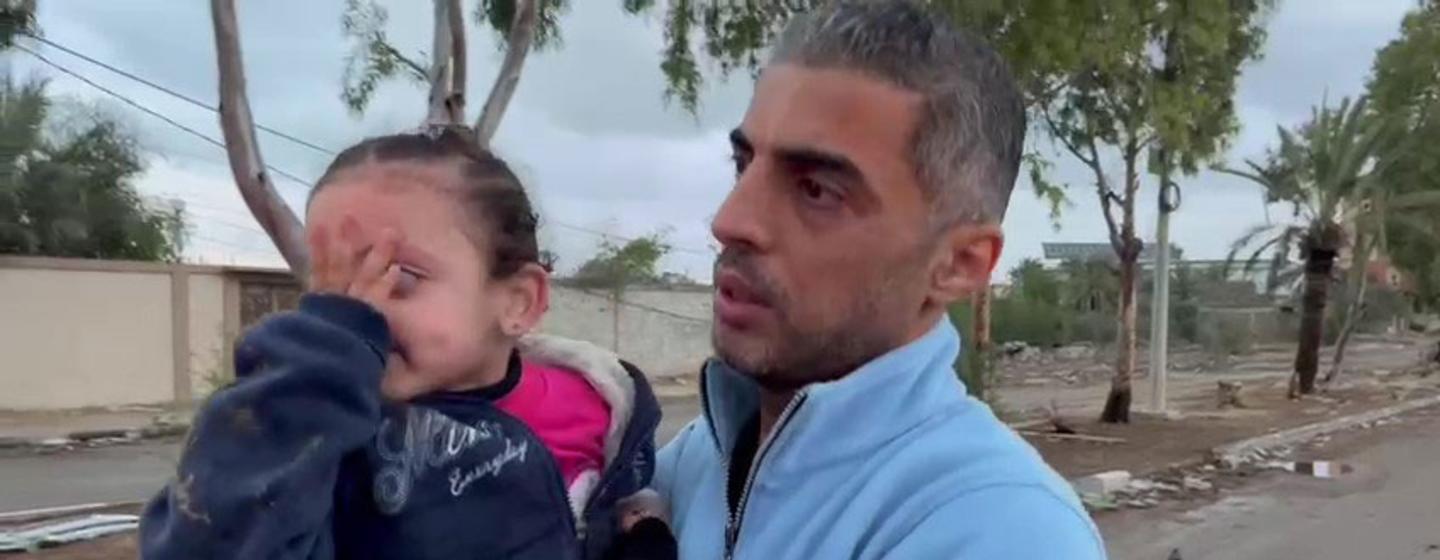 加沙地带巴勒斯坦红新月会应急和灾害管理主任穆哈默德协助接收一名流离失所的母亲和她的两个女儿，他们穿过检查站，将前往加沙南部。