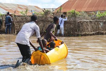 Children are ferried across flood water in a plastic barrel in Hirshabelle State, Somalia.