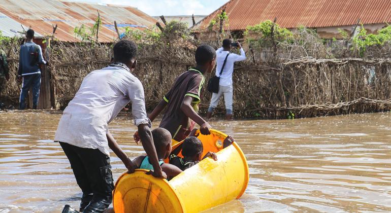 Children are ferried across flood water in a plastic barrel in Hirshabelle State, Somalia.