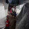 A woman walks with her children between several tents inside the displacement site at Jean Marie Césard School, Route de Frères, Port-au-Prince.
