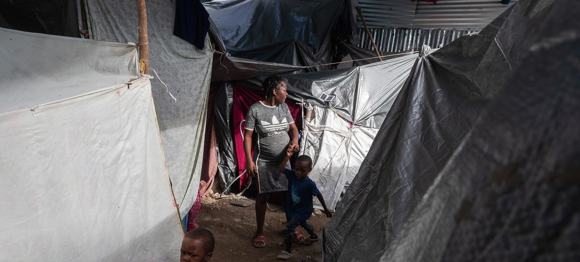 A woman walks with her children between several tents inside the displacement site at Jean Marie Césard School, Route de Frères, Port-au-Prince. A woman walks with her children between several tents inside the displacement site at Jean Marie Césard School, Route de Frères, Port-au-Prince.