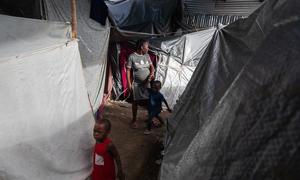 A woman walks with her children between several tents inside the displacement site at Jean Marie Césard School, Route de Frères, Port-au-Prince.