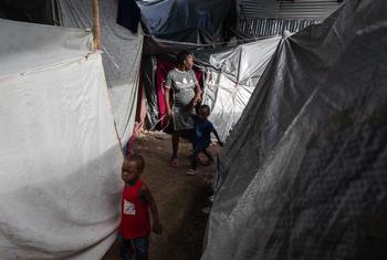 A woman walks with her children between several tents inside the displacement site at Jean Marie Césard School, Route de Frères, Port-au-Prince.