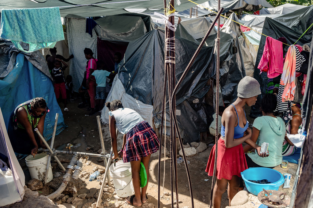 Scène de la vie quotidienne à côté de la fontaine d'eau à l'intérieur du site de déplacement de l'école Jean Marie Césard, Port-au-Prince.