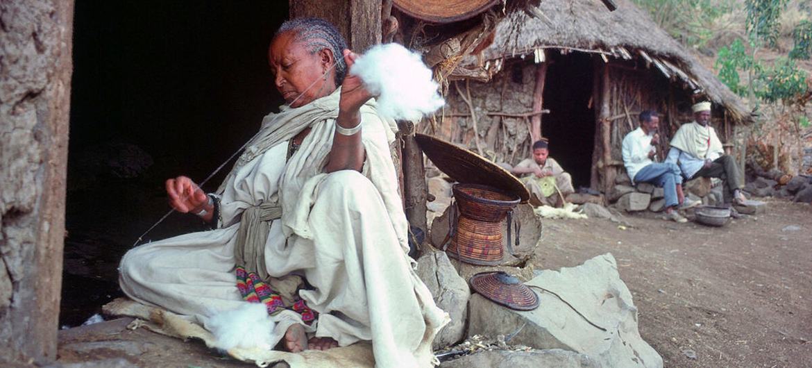 A rural woman spinning cotton at the entrance to her hut in Ethiopia.