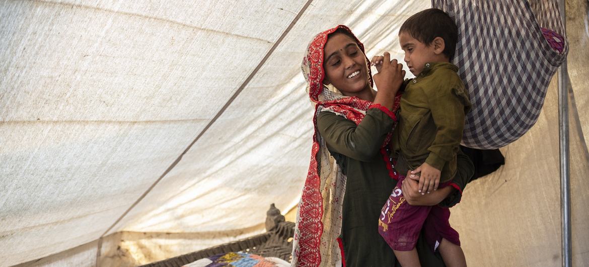 On 3 November 2022 in Jacobabad, Sindh province, Pakistan, 15-year-old Sugra, whose home was destroyed in recent floods, holds her brother, Fayaz.