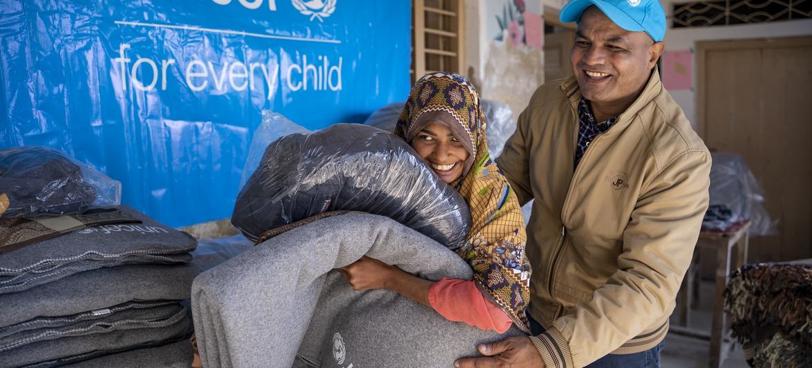 Le chef du bureau de terrain de l'UNICEF dans le Sindh - Prem Chand observe Rahman, 11 ans, porter une veste fournie par l'UNICEF lors de la distribution de kits d'hiver dans le village de Mitho Babbar, district de Dadu, province du Sindh.