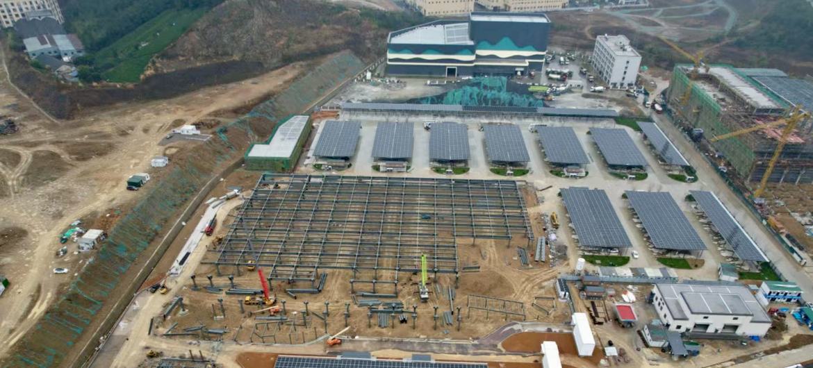 Aerial view of a construction site with multiple solar panel arrays and steel frameworks under development.