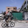 Un garçon fait du vélo à côté de bâtiments détruits après des attaques israéliennes dans la bande de Gaza, en Palestine, en mars 2022.