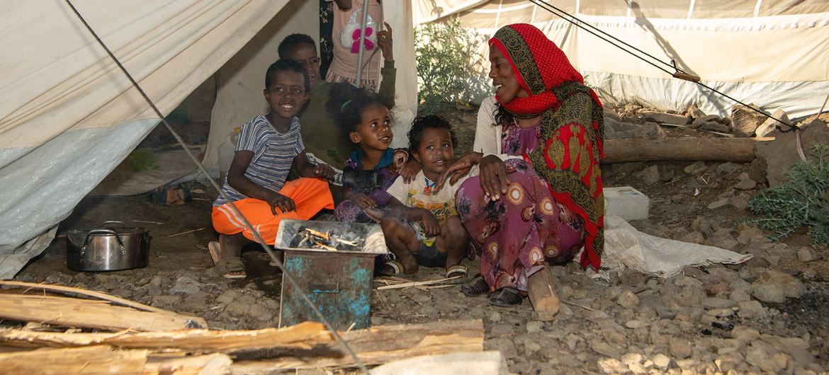 A family from Eritrea sit outside their shelter at a refugee site in the Amhara region of Ethiopia.