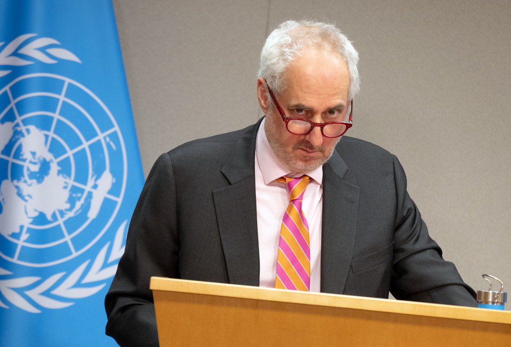 El portavoz de la ONU, Stéphane Dujarric, informa a los periodistas en un podio frente a una bandera de las Naciones Unidas.