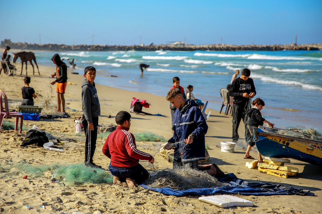 أشخاص، ومن بينهم أطفال، يقومون بالصيد على شاطئ البحر في مدينة غزة لتوفير الغذاء وسط الأعمال العدائية المستمرة في قطاع غزة.