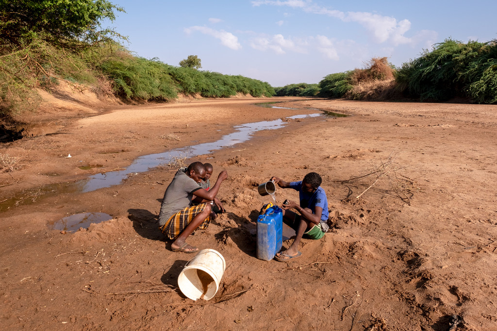 Un homme avec ses enfants collecte de l'eau de la rivière asséchée Dollow, en Somalie.