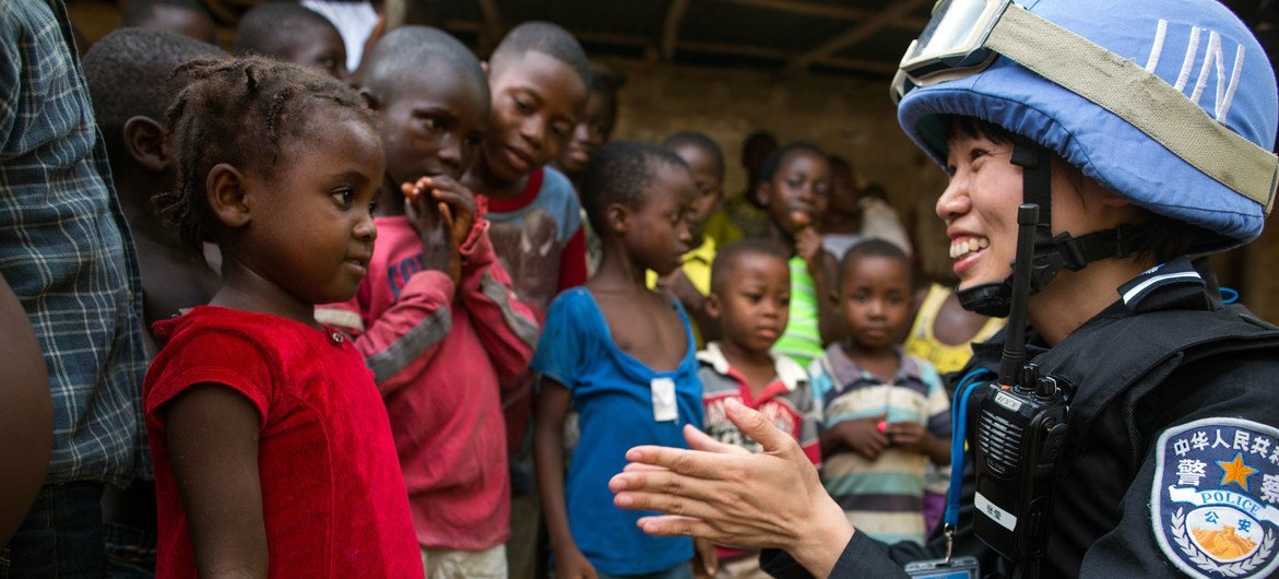 A Chinese police officer deployed to the UN Mission in Liberia (UNMIL) talks to a young girl whilst on patrol. 