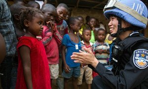 A Chinese police officer deployed to the UN Mission in Liberia (UNMIL) talks to a young girl whilst on patrol. 