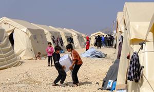 Children carry relief supplies at an IDP camp in Syria.
