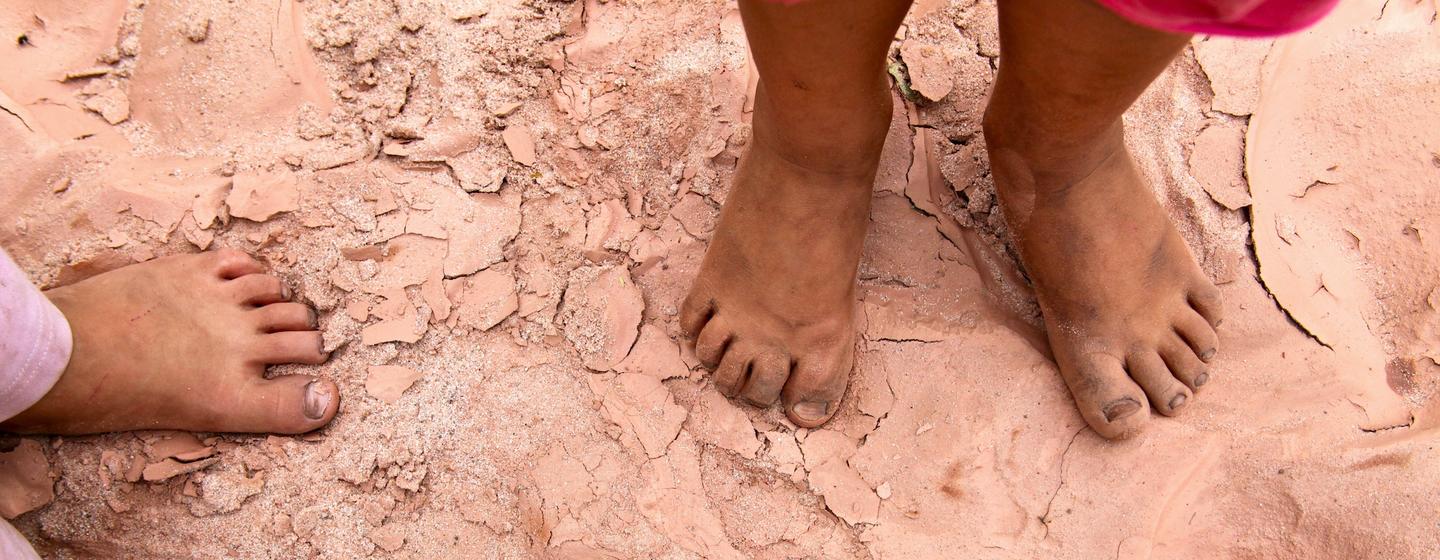 Deux enfants se tiennent pieds nus sur un sol craquelé et desséché dans le lit d'une rivière au sud de la Bolivie. (fichier)