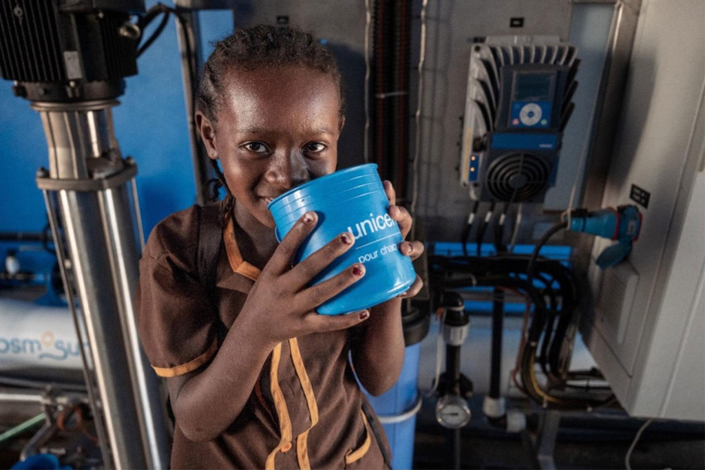 Une jeune écolière boit de l'eau provenant d'un système de déssalement soutenu par l'UNICEF.