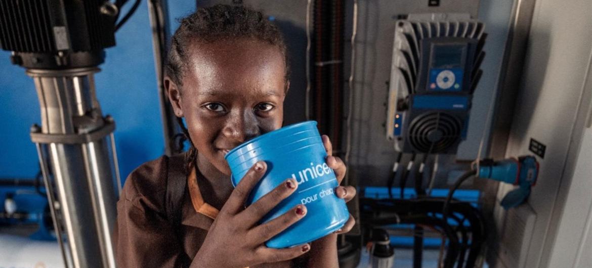Une jeune écolière boit de l'eau provenant d'un système de dessalement soutenu par l'UNICEF.