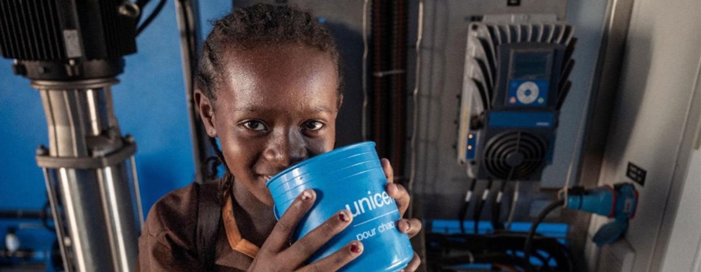 A young girl enjoys drinking water from a UNICEF-supported desalination system.