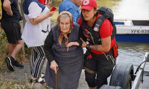 An elderly woman is evacuated from a flooded neighbourhood following the destruction of the Kakhovka dam in southern Ukraine.