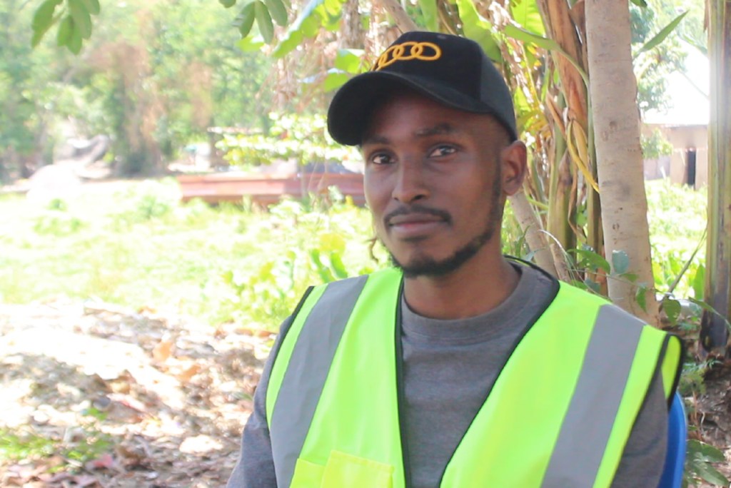 Zagalo Emmanuel, mwanzilishi wa mradi wa kuchakata taka za plastiki nchini Tanzania, akiwa amevaa fulana ya usalama na kofia.