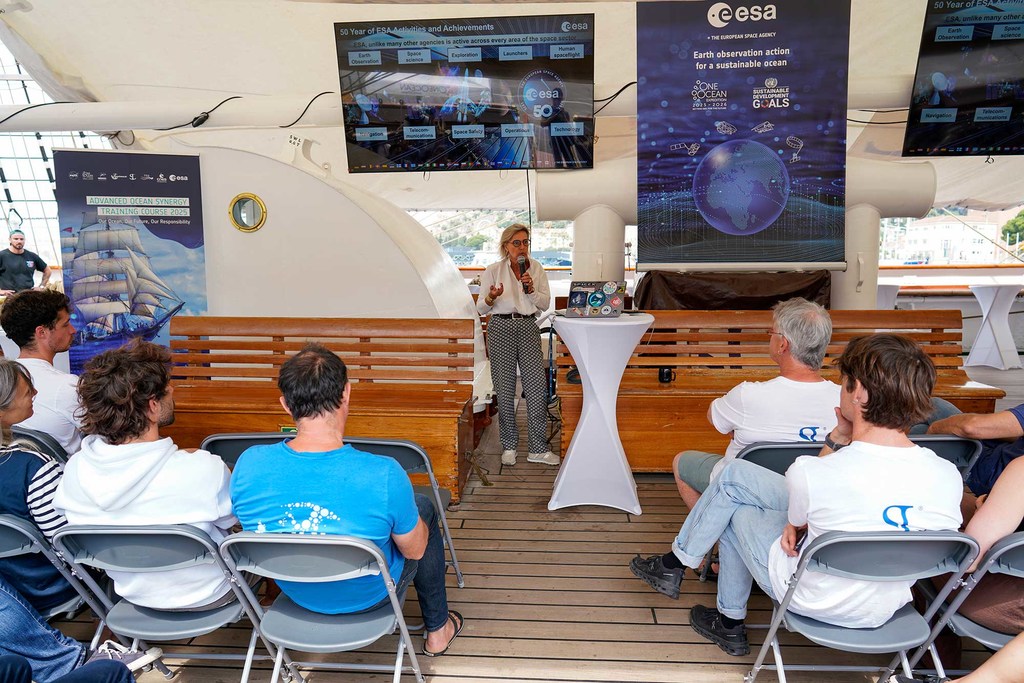 Simonetta Cheli, Director of ESA's Earth Observation, briefs a group of attendees at a training course on the deck of a ship.